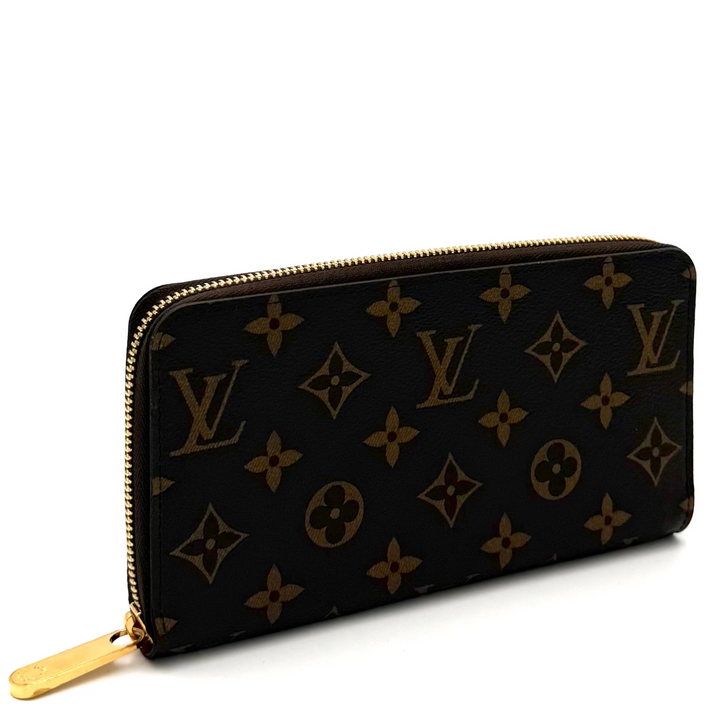 A Louis Vuitton monogram zip-around wallet in black coated canvas with gold-tone hardware, photographed on a white studio background.