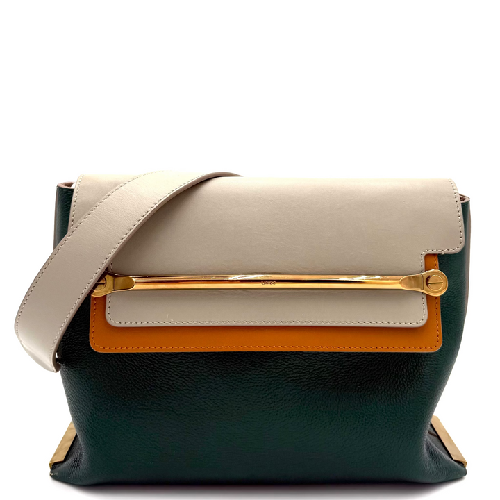 A structured leather shoulder bag with a color-blocked design featuring a dark forest green base, a cream flap, a cream horizontal band, and a bright orange accent panel, accented by a gold-tone bar and a matching cream strap.