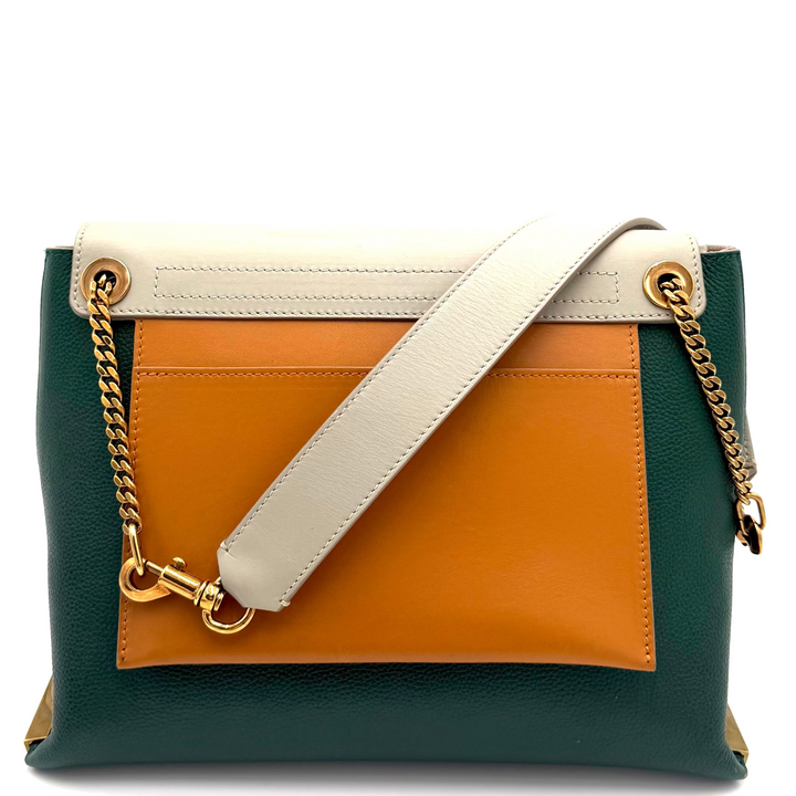 A color-blocked leather shoulder bag with a dark green base, a mustard yellow center panel, and a cream top flap and strap, featuring gold-tone chain and ring details, set against a plain white background.
