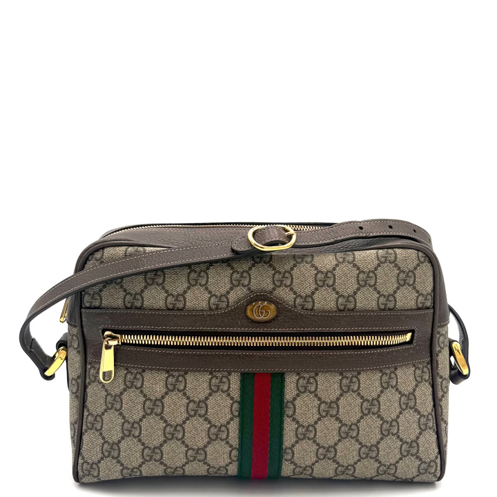 A Gucci crossbody bag in beige GG Supreme canvas with brown leather trim, a green and red web stripe, and gold-tone hardware, photographed against a white studio background.