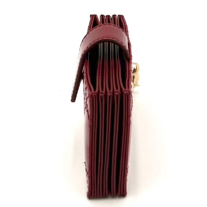 A small burgundy leather accessory, possibly a wallet or card holder, shown from the side on a plain white background.