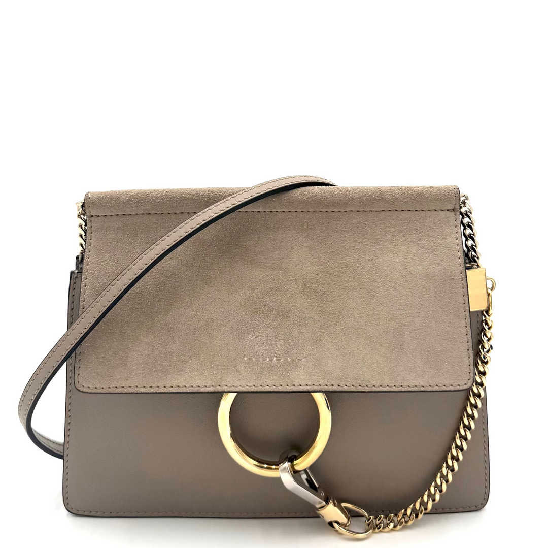A taupe leather shoulder bag with a gold-tone chain strap and a large circular gold ring detail on the front flap, shown against a plain white background.