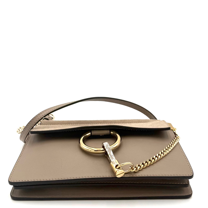 A structured taupe leather handbag with a gold-tone ring detail and chain strap, photographed on a clean white background.